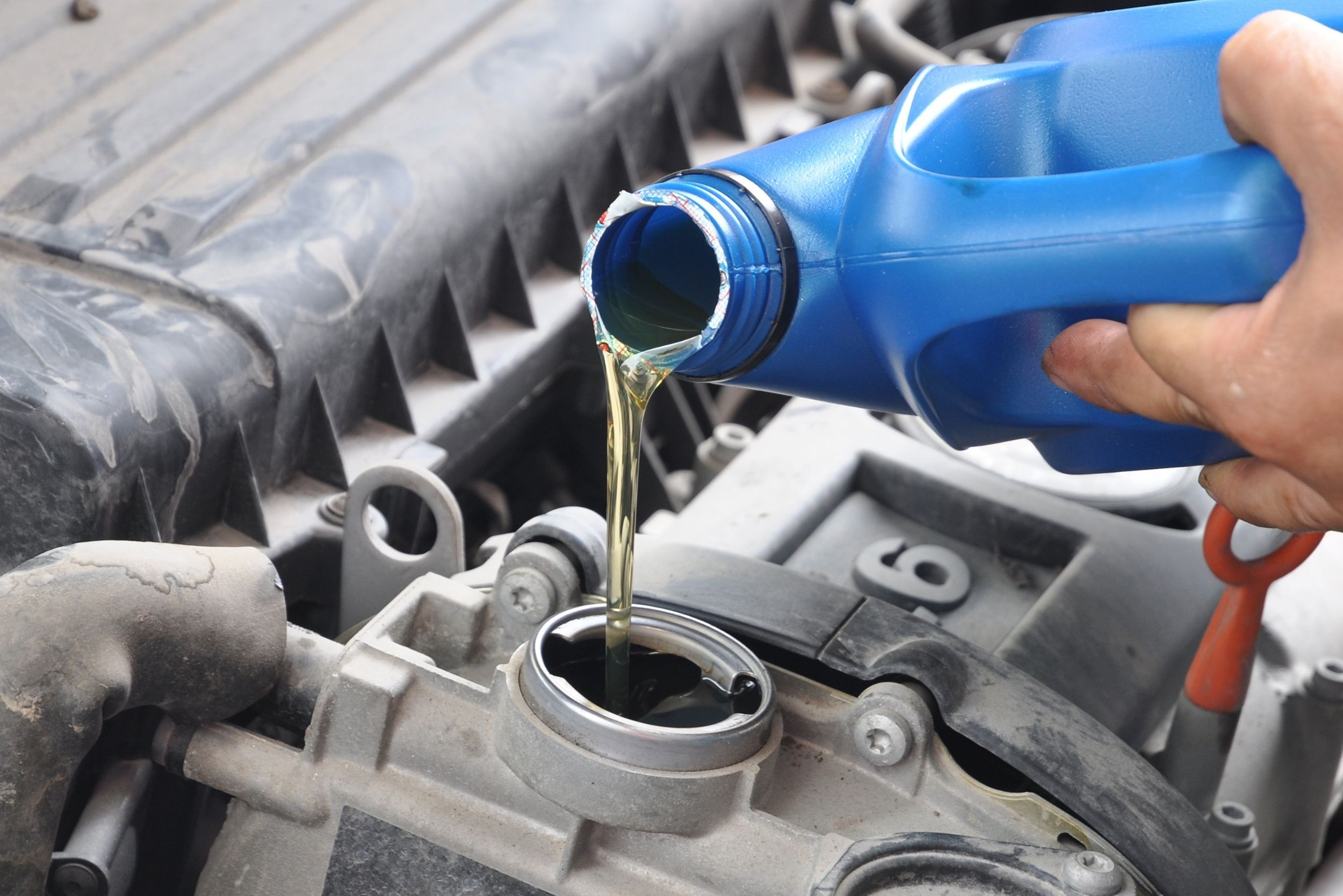 Oil being poured into a vehicle engine from a plastic container